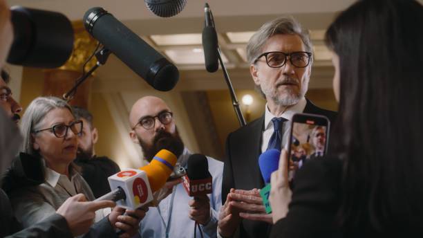 istock Mature diplomat surrounded by crowd of journalists 2148282444