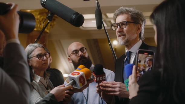 istock Mature diplomat surrounded by crowd of journalists 2148283806