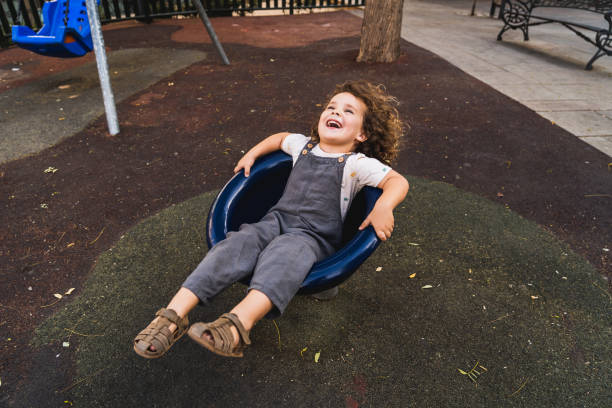 istock happy little boy playing spinning in playground 2148284077