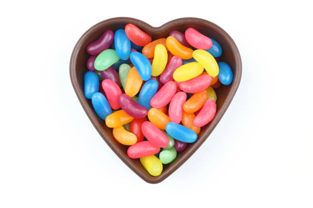 istock multi-colored sweet candies in heart shaped bowl on white background, top view. Space for text 2148284343