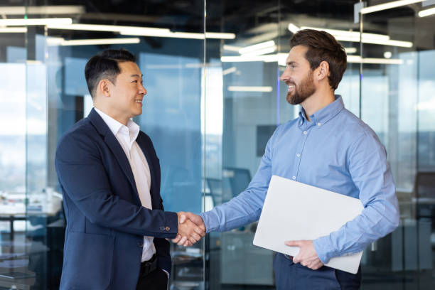 istock Two professional businessmen shaking hands in a modern office, partnership and teamwork concept 2148285834