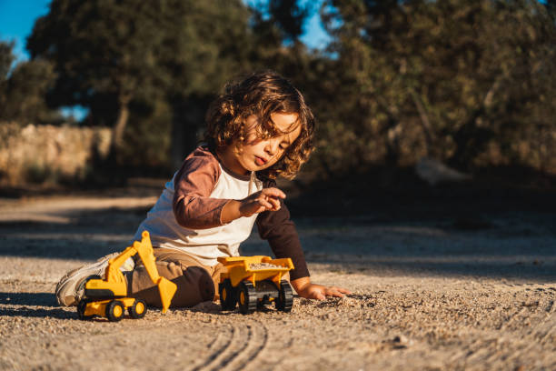 istock Nice happy little boy playing with excavator machine and truck under sunlight 2148285867