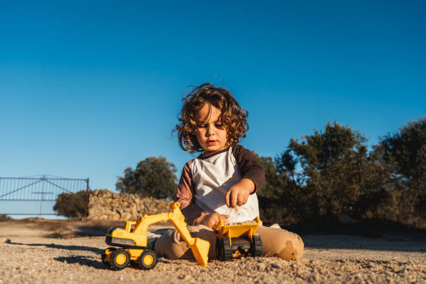 istock Nice happy little boy playing with excavator machine and truck under sunlight 2148285870