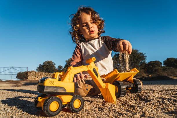 istock Nice happy little boy playing with excavator machine and truck under sunlight 2148285886