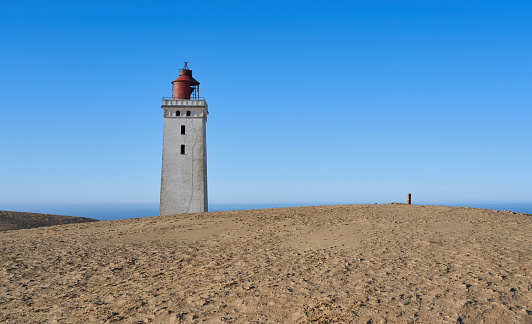 View of Rubjerg Knude lighthouse on sand dunes coast of North Sea In Jutland against clear blue sky during sunny day at Denmark