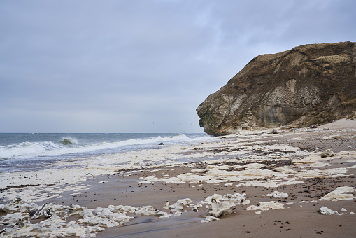 Scenic view of waves breaking in beautiful seascape and white rocks at sandy beach against cloudy sky at Frøstrup, Denmark