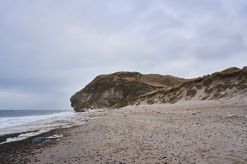 Scenic view of Baltic Sea beach with majestic cliff and sand dunes against cloudscape at Frøstrup, Denmark