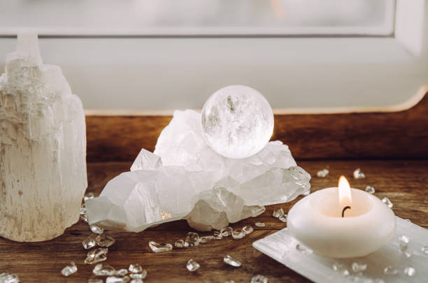 istock Gemstone sphere or crystal ball on quartz geode on wood tray, candle burning. Tranquil home concept. 2148286436