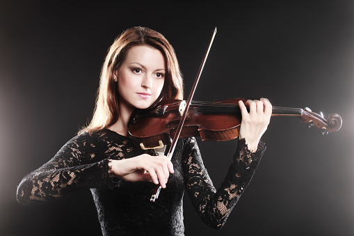 Charming girl violinist playing classical music. Isolated on white