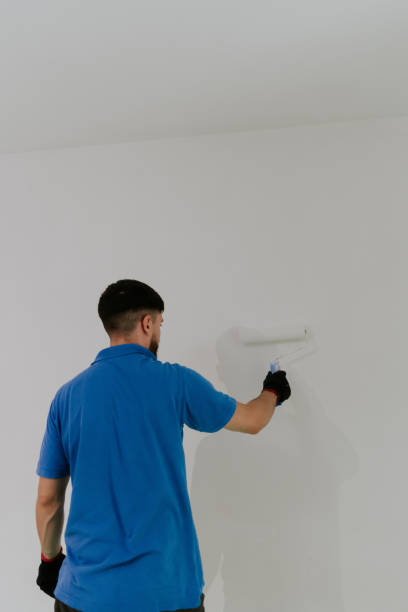 istock A young oriental man paints a wall with a roller. 2148286684