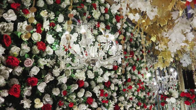 A close-up photo of the stage is decorated with colorful flowers and an elegant white chandelier suspended, enhancing its overall beauty.