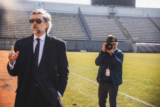 Photojournalist working at a soccer event on the field with the stadium in the background