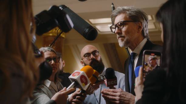 istock Mature diplomat surrounded by crowd of journalists 2148288060