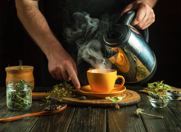 istock A man brews tea with medicinal herbs on the kitchen table. Traditional medicine concept at home. Adding boiling water to a mug 2148288396