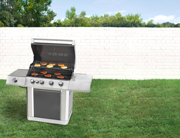 istock BBQ grill in a backyard with green grass and white brick wall 2148289057