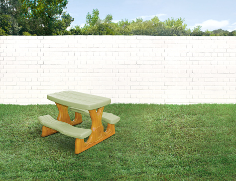 Kids small plastic bench in a empty backyard with green grass and wood fence