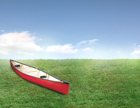 A red kayak in an empty backyard with green grass