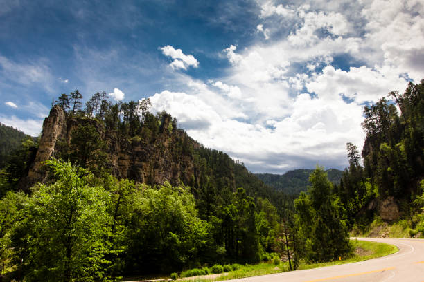 Single motorcycle riding down a long road in the lush green mountains
