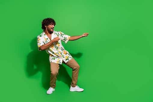 Full size photo of pretty young male pulling heavy object dressed stylish citrus print outfit isolated on green color background.