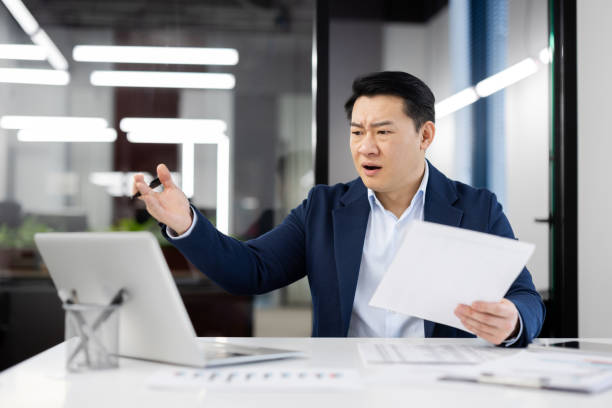 istock Frustrated businessman at desk with computer and papers 2148291688