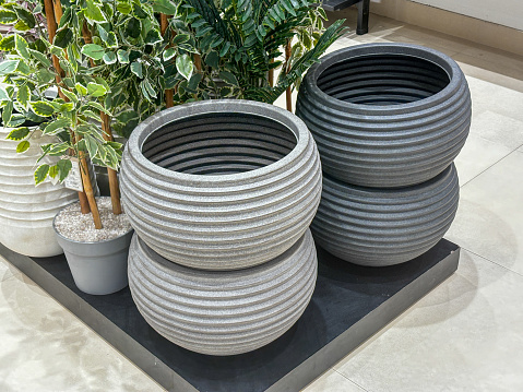 A row of three large, round, grey and black planters sit on a black surface. The planters are arranged in a row, with the middle one slightly larger than the other two