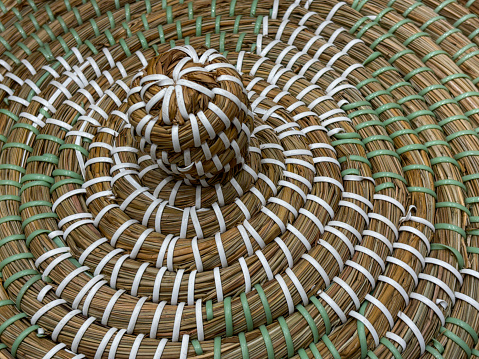 A woven object with a white and brown design. The object is a small round shape with a white center