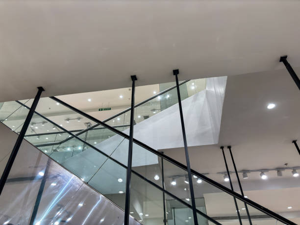 A glass staircase with a green sign on it. The sign says Exit. The staircase is in a building with many lights