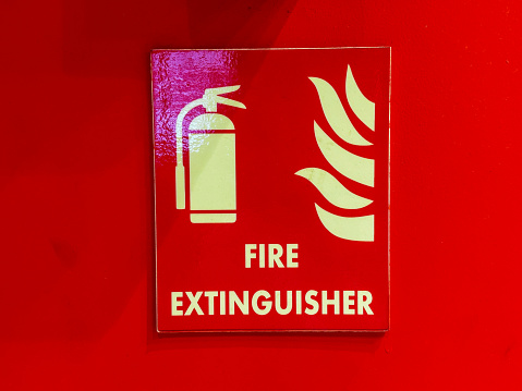 A red sign with a fire extinguisher on it. The sign is yellow and white