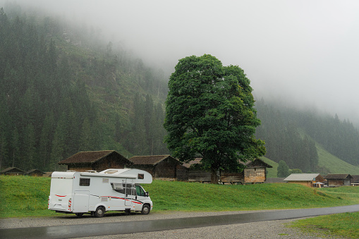 Camper van parked by the road during heavy rain in Swiss Alps