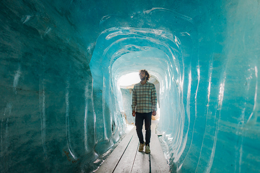 Amazed man exploring ice cave in Rhone Glacier