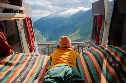 Woman laying in camper van overlooking Furka Pass in Switzerland during her vacation
