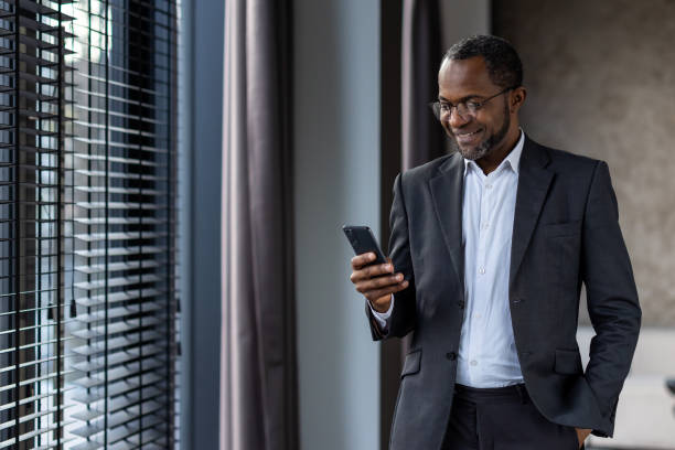 istock Professional african american businessman smiling while using smartphone indoors 2148294472
