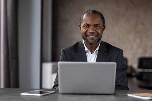 istock A man in a suit is sitting at a desk with a laptop and tablet 2148294510