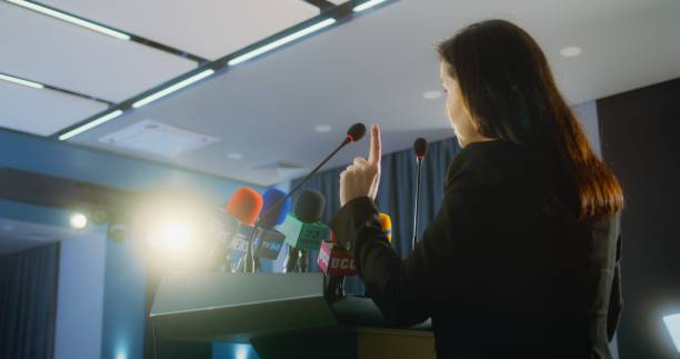 istock Female press officer pronounces speech from tribune during press campaign 2148294553