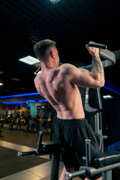 istock in the gym a young handsome guy with tattoos is doing pull-ups on the horizontal bar shaking his back and arms 2148295171