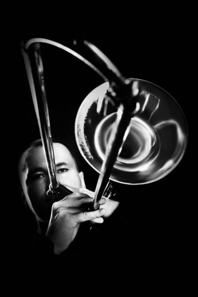 Trombone player. Trombonist playing jazz musician. Man playing brass instrument isolated on black