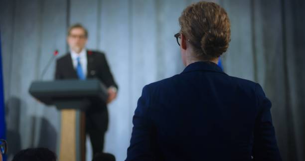 istock Female representative of media stands up and asks question 2148296391
