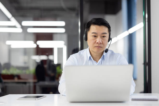 istock Focused professional with headset working on laptop in office 2148296643