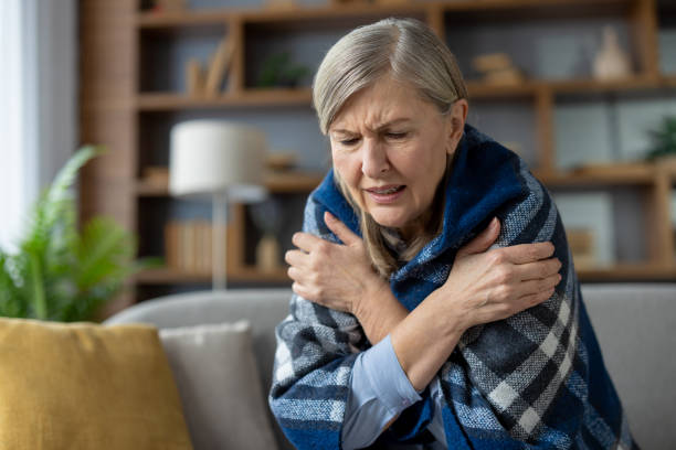 istock Senior woman feeling cold, wrapped in a warm blanket at home 2148296952