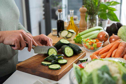 Male hands holding cutting board with sliced fresh vegetables