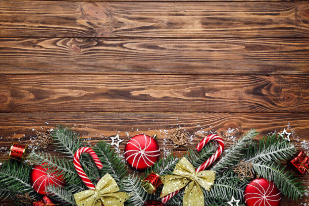 istock Fir tree branches with christmas ornaments on brown wooden table 2148297527