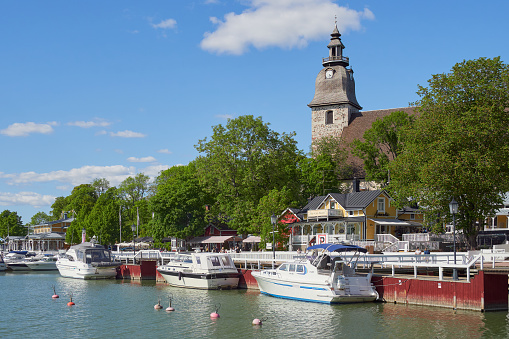 Finland, Naantali - June 9, 2023. Embankment in the old center of the Finnish town of Naantali in Europe: Lutheran church, old wooden houses, yachts.