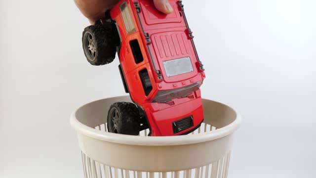 A broken children's toy car is thrown into the garbage can. Recycling of plastics.