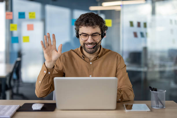 istock Smiling businessman in headset waving during video call 2148298010