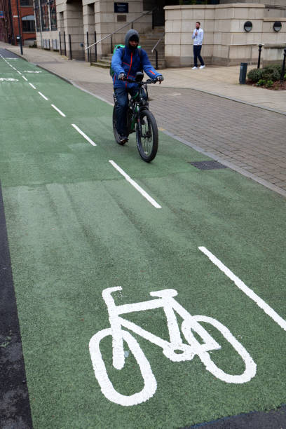 Leeds, UK 04 11 2024 Bicycle courier on an electric bike is seen travelling on a green tarmac cycle lane, with cycle logo in white in foreground