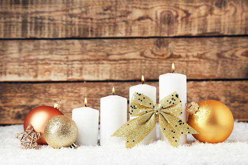 Rustic gold glowing candles with pine tree branch and Christmas ornament.