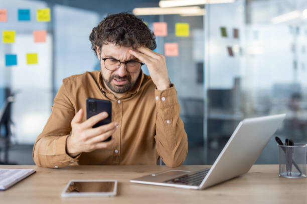 istock Hispanic man confused and upset using smartphone in office 2148298269