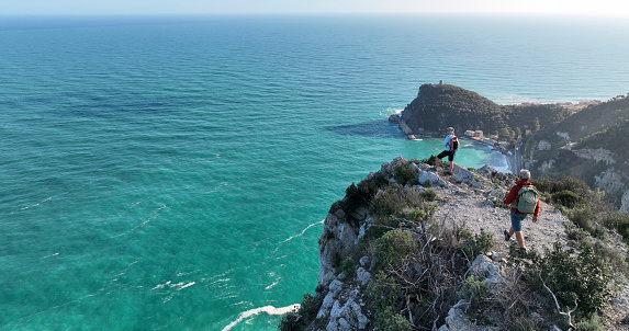 Aerial view of mature couple hiking on cliff above sea,  Liguria