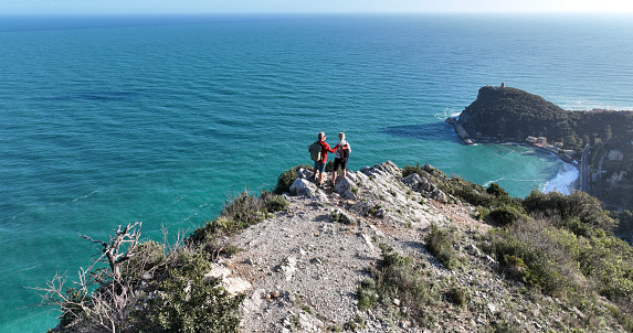 Aerial view of mature couple hiking on cliff above sea,  Liguria