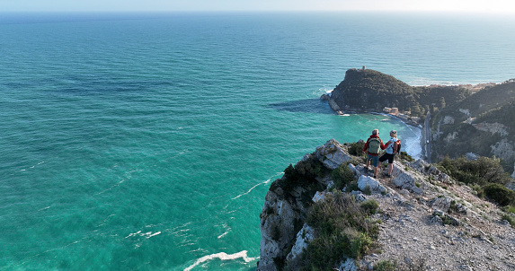 Aerial view of mature couple hiking on cliff above sea,  Liguria